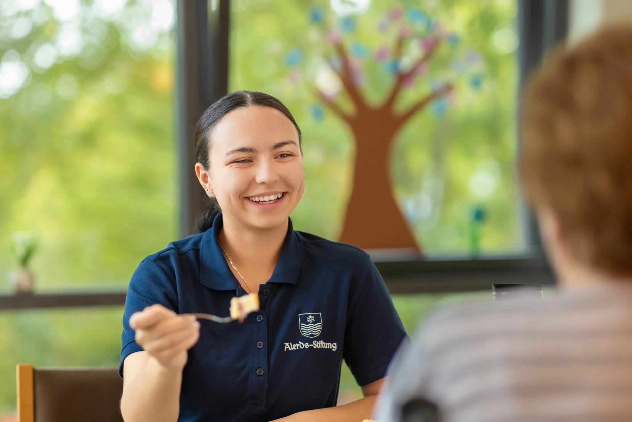 Betreuungskraft hilft Seniorin beim Essen